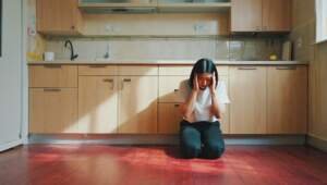 Flooring Fail Trends 2025 - person looking on the floors - holding their head very unhappy in the kitchen area, hardwood floors don't match the cabinets