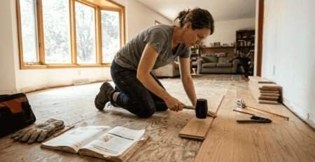 Homeowner installing hardwood planks in living room